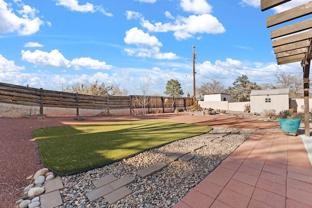 view of yard with an outdoor structure, a fenced backyard, and a patio area