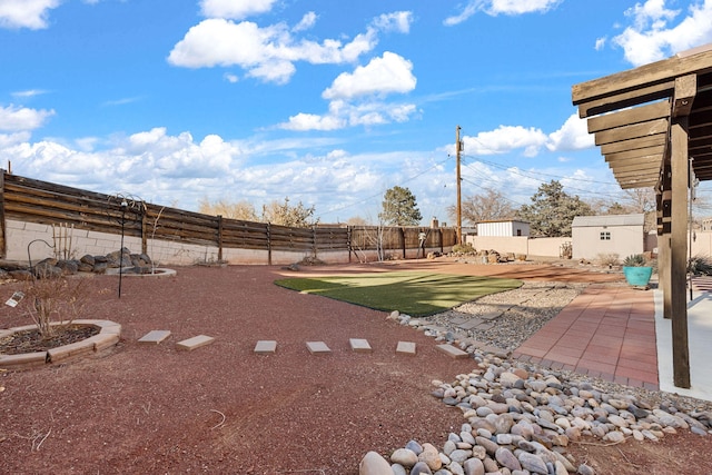 view of yard featuring a patio area, an outdoor structure, and a fenced backyard