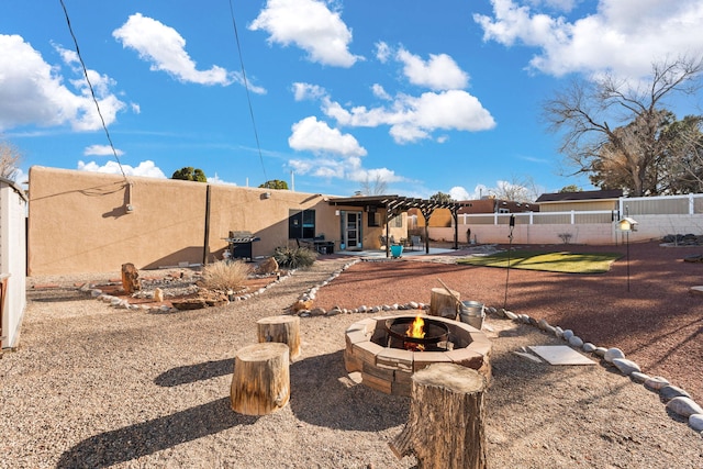 back of property featuring stucco siding, a pergola, a patio, fence, and a fire pit