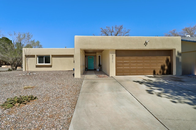 pueblo revival-style home with a garage, driveway, and stucco siding