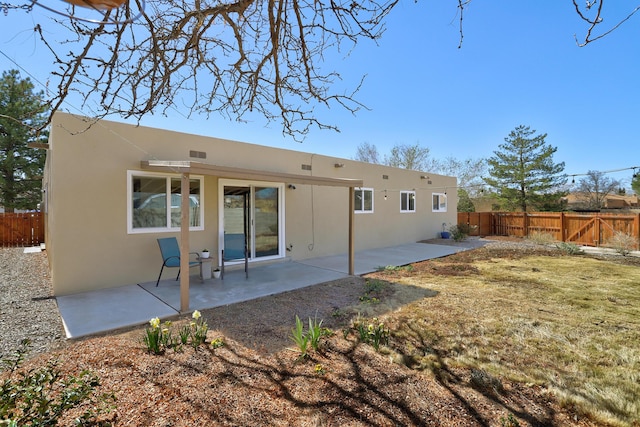 rear view of property featuring a patio area, stucco siding, a yard, and fence