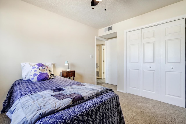 bedroom with visible vents, ceiling fan, carpet floors, a closet, and a textured ceiling