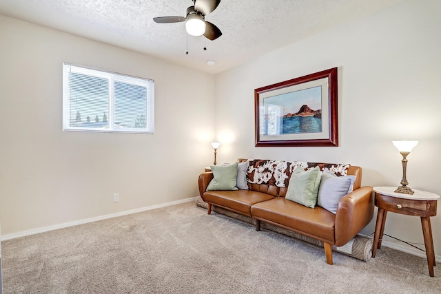 living area featuring a ceiling fan, baseboards, a textured ceiling, and carpet flooring