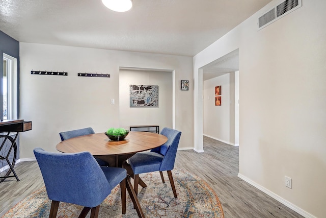 dining space with wood finished floors, visible vents, and baseboards