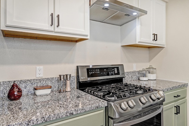 kitchen with gas stove, light stone counters, wall chimney exhaust hood, and white cabinetry