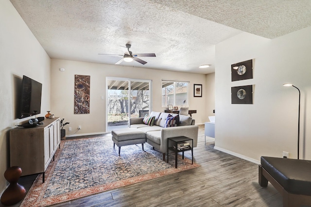 living room with a textured ceiling, baseboards, ceiling fan, and wood finished floors