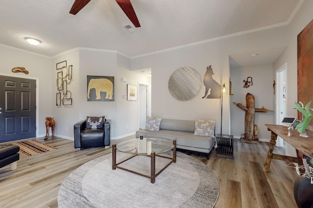 living room with a ceiling fan, wood finished floors, baseboards, and ornamental molding