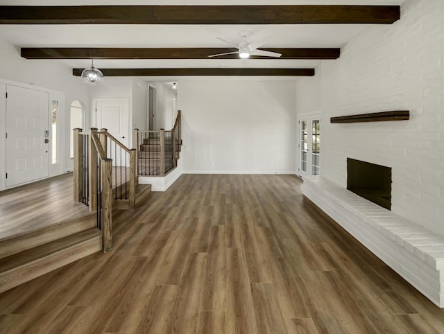 unfurnished living room featuring ceiling fan, baseboards, stairway, a fireplace, and wood finished floors