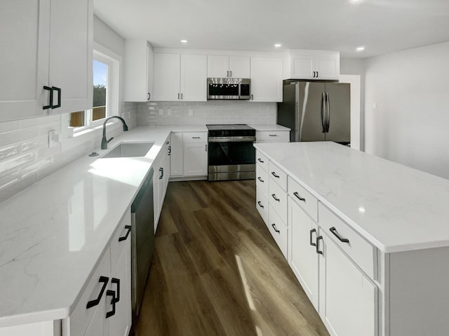 kitchen with a sink, backsplash, a center island, stainless steel appliances, and dark wood-style flooring