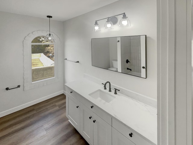 bathroom featuring a chandelier, vanity, baseboards, and wood finished floors