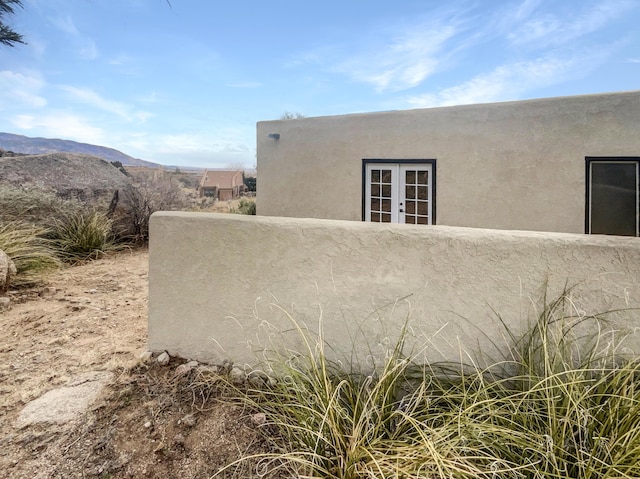 view of property exterior featuring french doors, a mountain view, and stucco siding