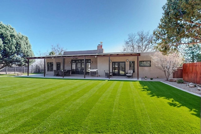 rear view of property featuring a patio area, fence, and stucco siding