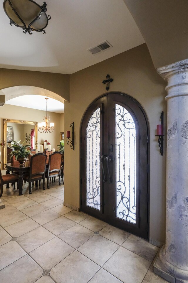 entryway featuring visible vents, arched walkways, light tile patterned flooring, and a chandelier