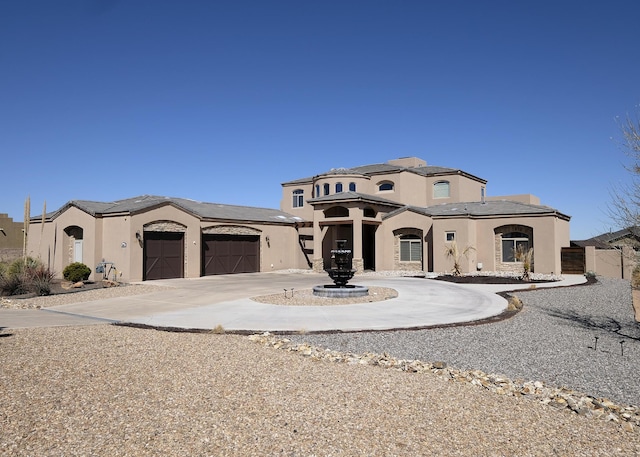 mediterranean / spanish house with stucco siding, curved driveway, and a garage