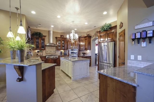 kitchen featuring backsplash, arched walkways, appliances with stainless steel finishes, a peninsula, and wall chimney range hood