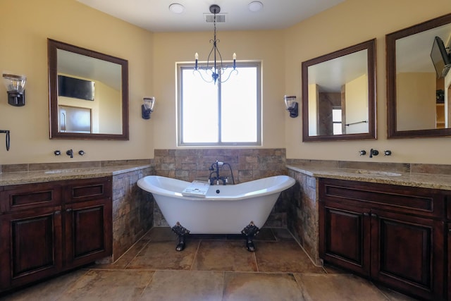 bathroom featuring visible vents, a wainscoted wall, two vanities, a soaking tub, and tile walls