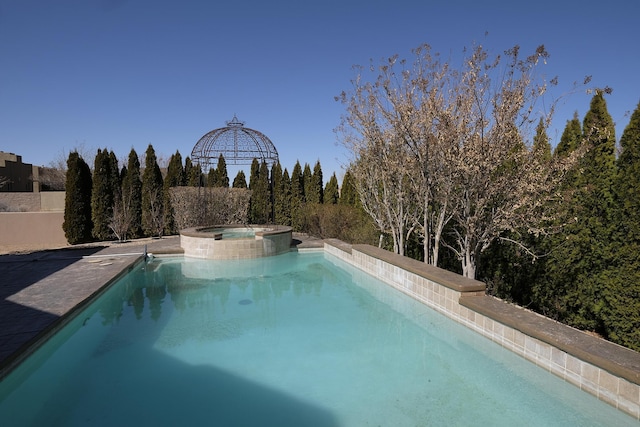 view of pool with a pool with connected hot tub