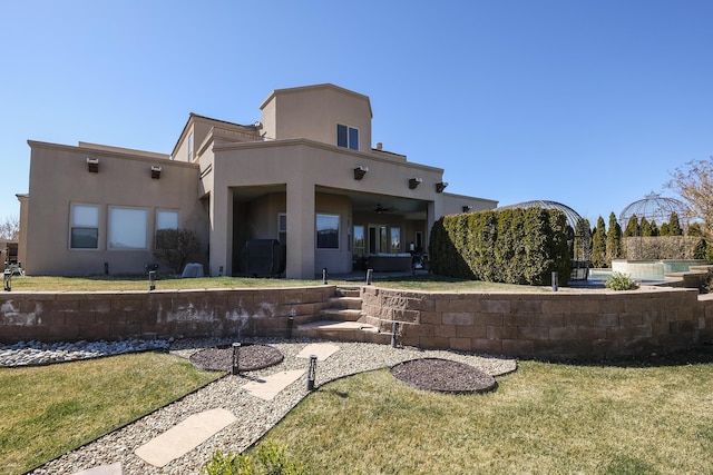 back of property featuring a lawn and stucco siding