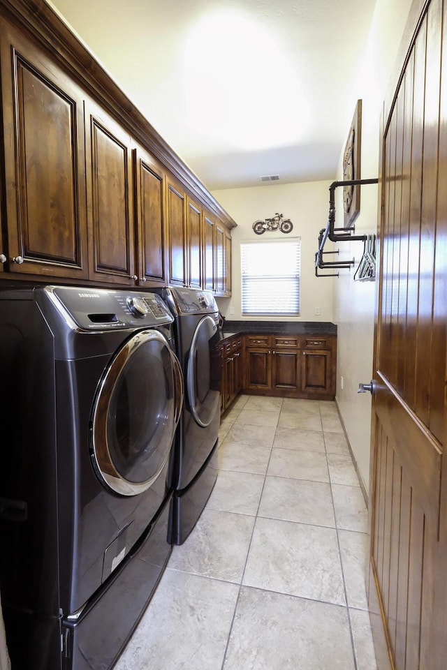 laundry area featuring light tile patterned floors, cabinet space, and washing machine and clothes dryer