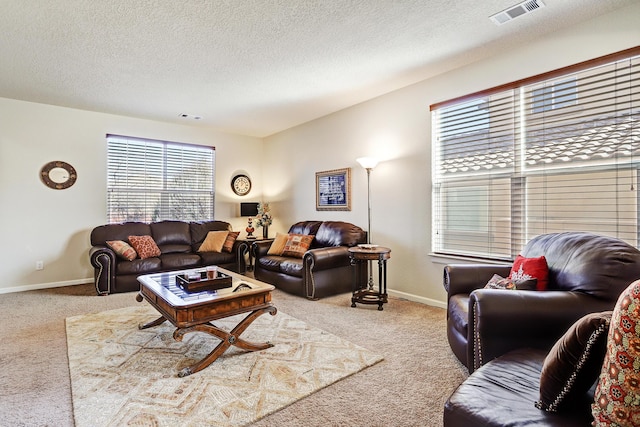 living room featuring baseboards, carpet, visible vents, and a textured ceiling