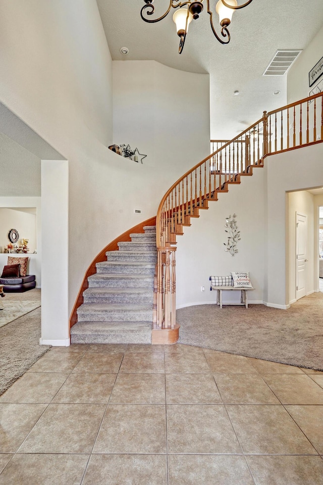 staircase with tile patterned flooring, visible vents, a high ceiling, and carpet