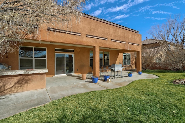 back of house with a patio, a yard, and stucco siding