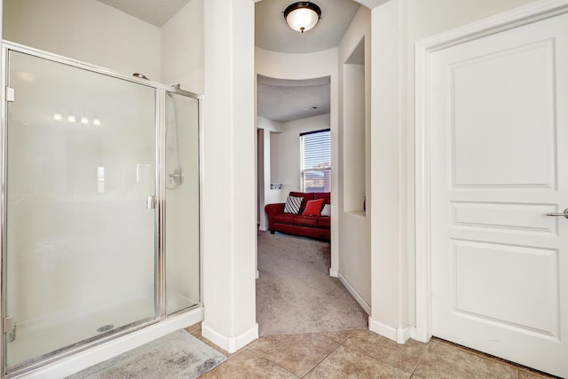 ensuite bathroom featuring a stall shower, a textured ceiling, ensuite bath, tile patterned flooring, and baseboards