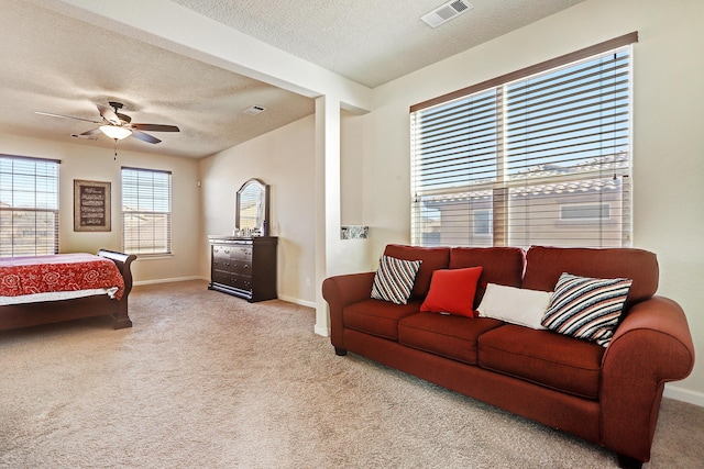 interior space featuring visible vents, baseboards, carpet flooring, a textured ceiling, and a ceiling fan