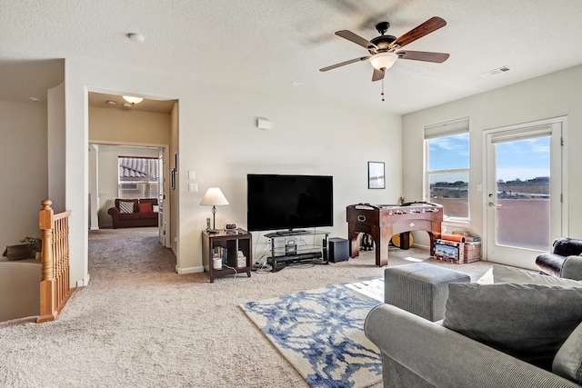 living room with carpet, baseboards, visible vents, ceiling fan, and a textured ceiling