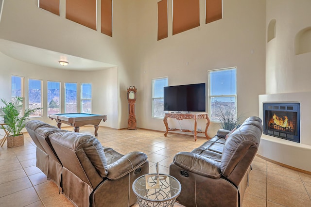 living area featuring tile patterned floors, a warm lit fireplace, billiards, and baseboards