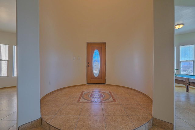 tiled foyer featuring baseboards and a towering ceiling