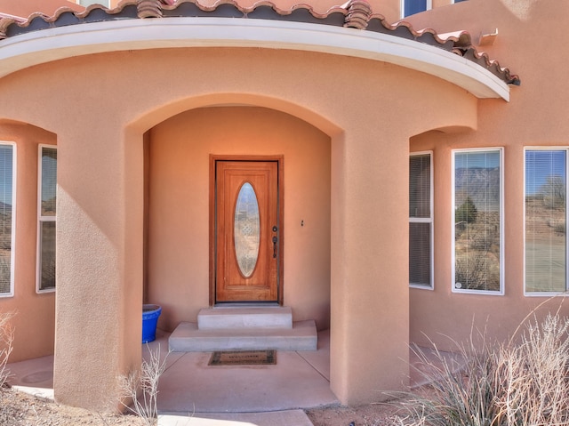 doorway to property featuring stucco siding and a tile roof