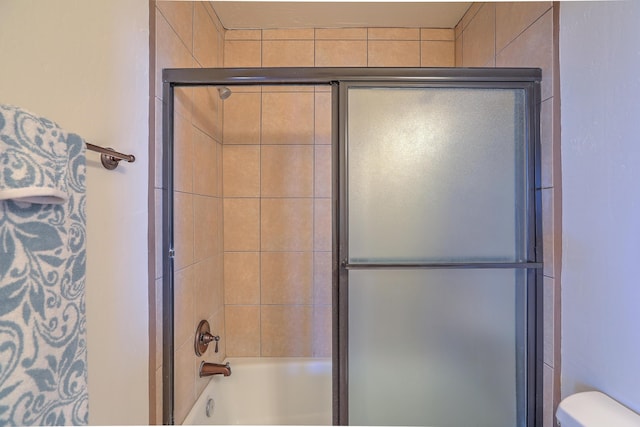 full bath featuring toilet and bath / shower combo with glass door