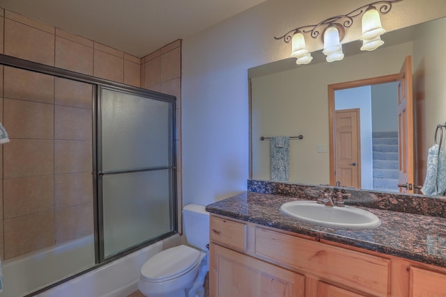 bathroom with vanity, toilet, and combined bath / shower with glass door