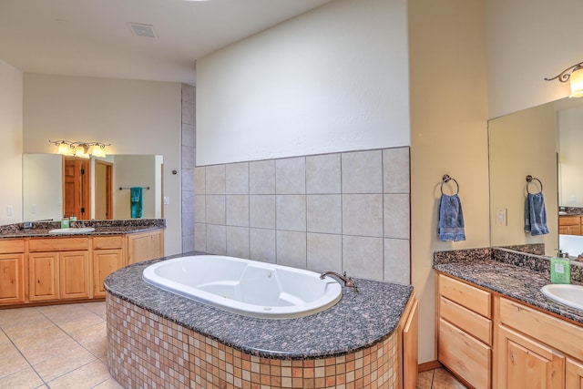 bathroom with tile patterned flooring, two vanities, a bath, and a sink