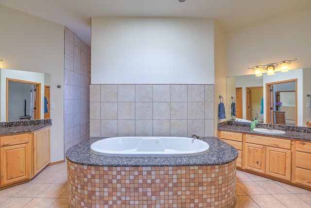 full bathroom featuring tile patterned floors, two vanities, a bath, and a sink