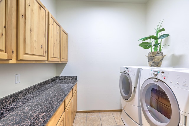 clothes washing area featuring washer and dryer, baseboards, cabinet space, and light tile patterned flooring