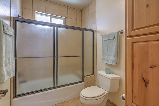 bathroom with tile patterned flooring, toilet, and combined bath / shower with glass door