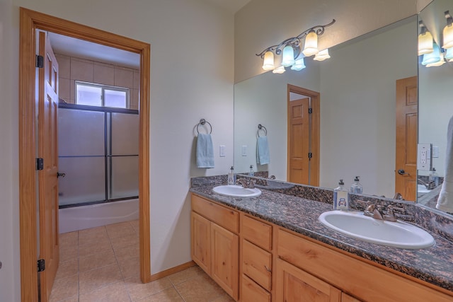 full bath with a sink, bath / shower combo with glass door, double vanity, and tile patterned flooring