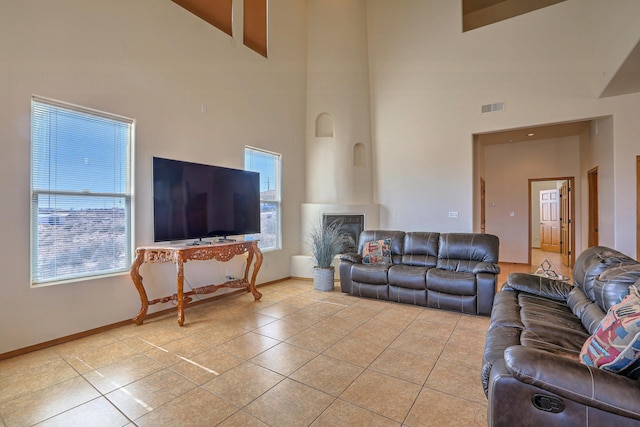 living room with a high ceiling, light tile patterned flooring, baseboards, and visible vents