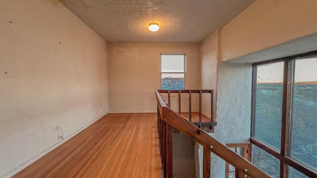 3805 Riverview Rd NW, Albuquerque, NM 87105 - hallway with an upstairs landing, light wood-type flooring, healthy amount of natural light, a textured ceiling, and a textured wall