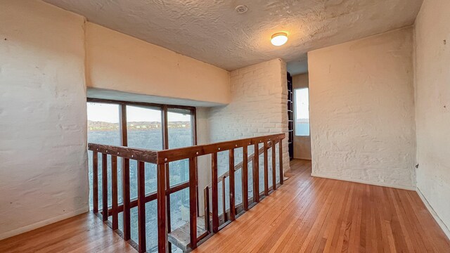 3805 Riverview Rd NW, Albuquerque, NM 87105 - hallway featuring hardwood / wood-style flooring, an upstairs landing, a textured wall, and a textured ceiling