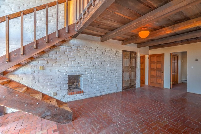 3805 Riverview Rd NW, Albuquerque, NM 87105 - unfurnished living room featuring a wood ceiling with exposed beams, brick flooring, a brick fireplace, stairs, and a baseboard radiator
