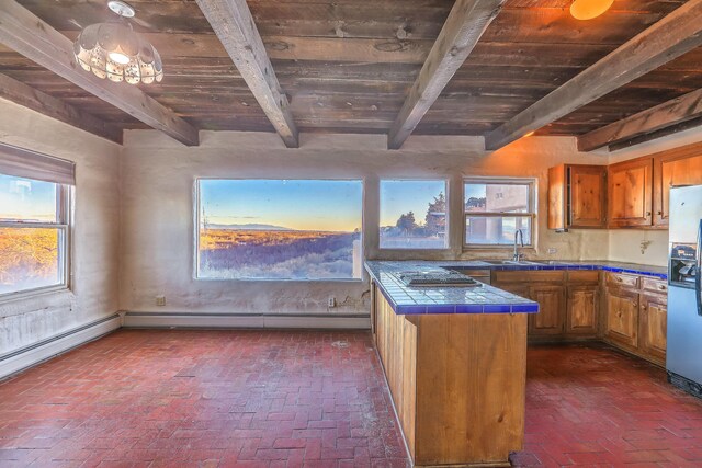 3805 Riverview Rd NW, Albuquerque, NM 87105 - kitchen with tile counters, brick flooring, a wooden ceiling with exposed beams, brown cabinetry, and stainless steel appliances