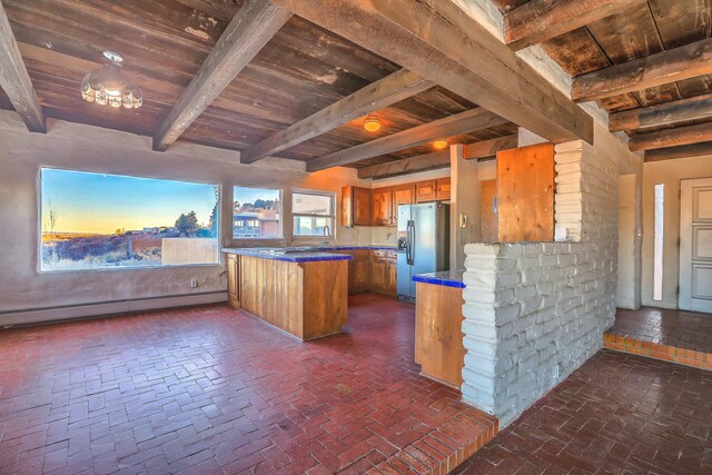 3805 Riverview Rd NW, Albuquerque, NM 87105 - kitchen featuring stainless steel fridge, brown cabinetry, a baseboard heating unit, a wooden ceiling with exposed beams, and a peninsula