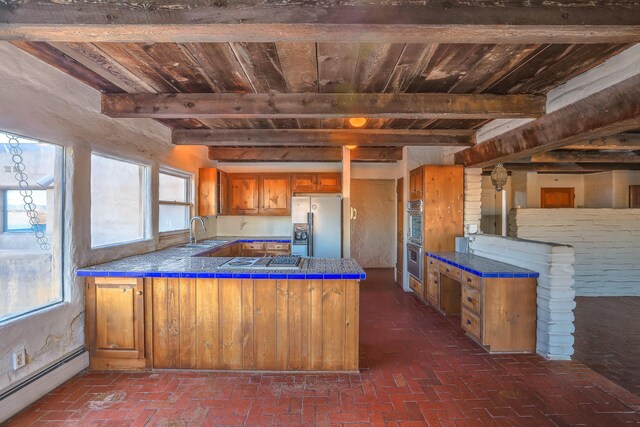 3805 Riverview Rd NW, Albuquerque, NM 87105 - kitchen with appliances with stainless steel finishes, a baseboard heating unit, a wood ceiling with exposed beams, tile counters, and a peninsula