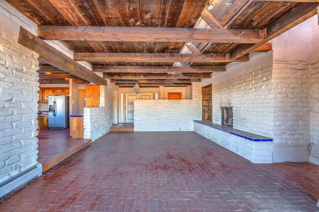 3805 Riverview Rd NW, Albuquerque, NM 87105 - unfurnished living room featuring a baseboard heating unit, a fireplace, brick flooring, and a wood ceiling with exposed beams