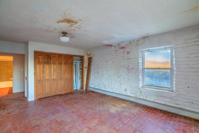 3805 Riverview Rd NW, Albuquerque, NM 87105 - unfurnished bedroom featuring brick floors, a closet, and a baseboard heating unit