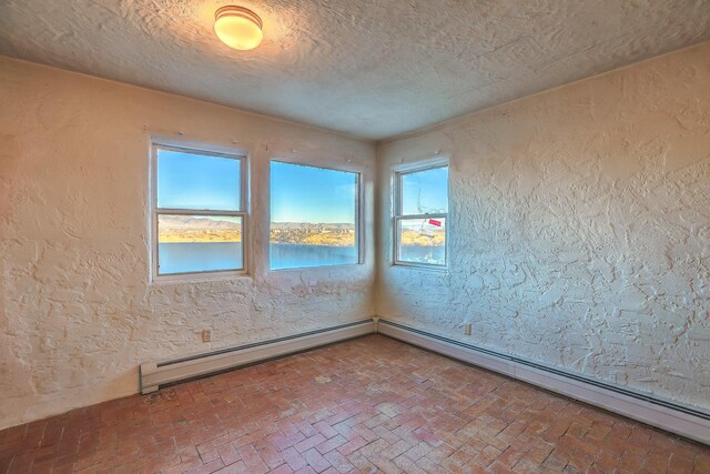 3805 Riverview Rd NW, Albuquerque, NM 87105 - empty room with a textured wall, brick floors, and a baseboard heating unit