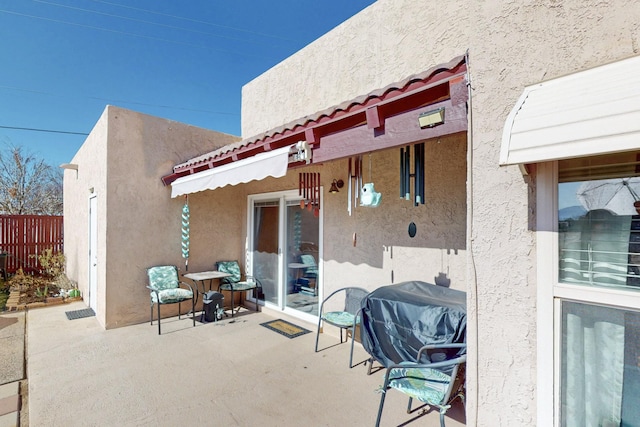 view of patio featuring a grill and fence